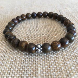 May include: A brown wooden beaded bracelet with a silver bead accent.