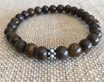 May include: A brown wooden beaded bracelet with a silver bead accent.