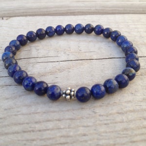 May include: A blue lapis lazuli beaded bracelet with a silver bead charm.