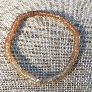 May include: A light brown beaded bracelet with a gold clasp.
