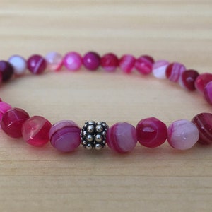 May include: A pink and white agate beaded bracelet with a silver bead accent.