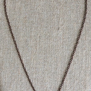Puede incluir: Un collar de cadena de cobre con un colgante redondo con una piedra de lapisl&aacute;zuli azul.