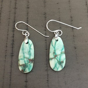 Peut inclure: Une paire de boucles d'oreilles en argent avec des pierres ovales vertes et blanches. Les pierres ont un motif marbré.