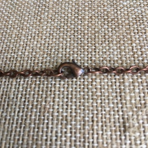 Puede incluir: Primer plano de un collar de cadena de cobre con un cierre de langosta.