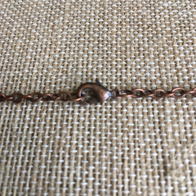Puede incluir: Primer plano de un collar de cadena de cobre con un cierre de langosta.