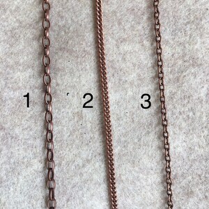 Puede incluir: Tres estilos diferentes de cadena de cobre, etiquetados como 1, 2 y 3. Las cadenas se muestran sobre un fondo marr&oacute;n claro.