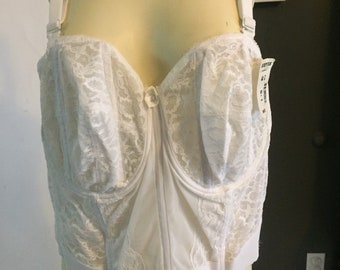 May include: White lace undergarment with adjustable straps and a hook and eye closure in the front. The garment has a size tag that reads "44".