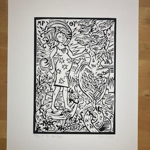 May include: Black and white linocut print depicting a woman in a star-patterned dress, standing before a multi-headed creature. The print includes the text "Mary of the Apocalypse" and the artist's signature. The artwork is mounted on a white background.