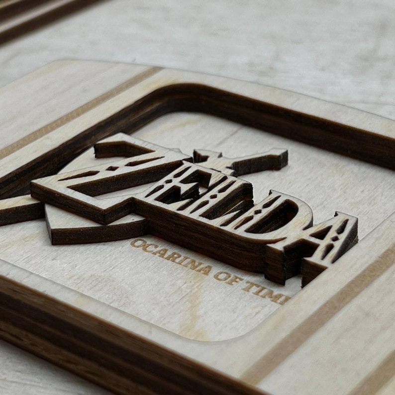 May include: A wooden sign with the words "Zelda Ocarina of Time" carved into it. The letters are layered and have a 3D effect.