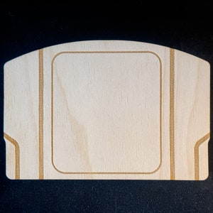 May include: A blank wooden Nintendo 64 game cartridge case with a light brown wood grain. The case has a rectangular opening in the centre and is outlined with a thin brown line.