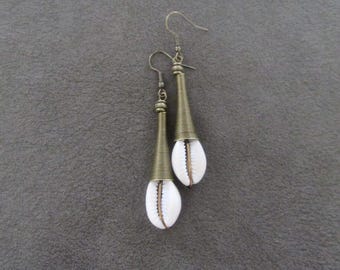 May include: A pair of gold-toned earrings with white cowrie shells hanging from the bottom. The earrings are made of wire and have a conical shape.