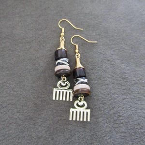 May include: A pair of gold earrings with black, white, and brown beads and a gold comb charm.