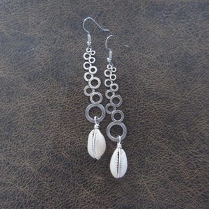 May include: Silver hoop earrings with a white shell charm hanging from each hoop.