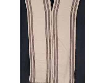 May include: A white woven poncho with black and red stripes. The poncho has a V-neck and a fringe border.