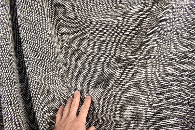 Puede incluir: Primer plano de una tela gris texturizada con una mano descansando sobre la superficie.