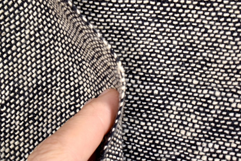 Puede incluir: Primer plano de una tela tejida en blanco y negro con un patr&oacute;n texturizado. La tela est&aacute; doblada por la mitad, revelando el tejido.