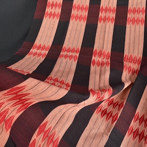 Könnte beinhalten: Gemustertes Textil mit vertikalen Streifen in Rot, Schwarz und Beige. Die roten Streifen weisen ein rautenförmiges Design auf. Der Stoff ist drapiert und zeigt seine Textur und seinen Fluss. Dunkler Hintergrund.