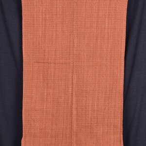 Peut inclure: Une &eacute;charpe tiss&eacute;e de couleur rouille avec un col en V et une bordure &agrave; franges.