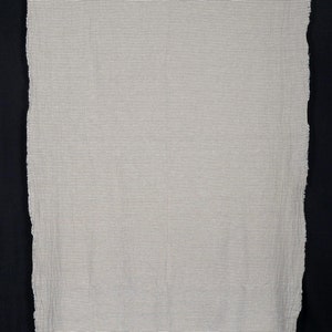 Peut inclure: Un tissu blanc avec de fines rayures noires. Le tissu a un bord brut et non fini.