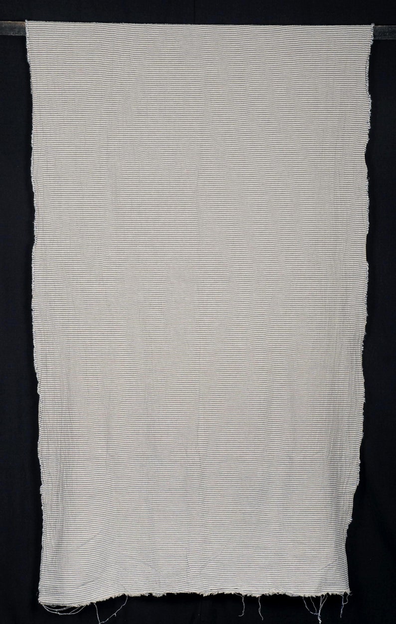 Peut inclure: Un tissu blanc avec de fines rayures noires. Le tissu a un bord brut et non fini.