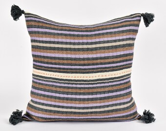 May include: A striped throw pillow with tassels in a variety of shades of brown, purple, and cream.