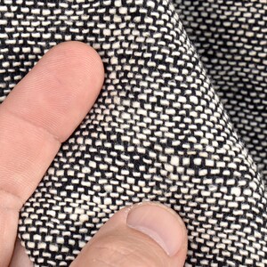 Puede incluir: Primer plano de una tela tejida en blanco y negro con un patr&oacute;n texturizado. La tela es suave y tiene un brillo sutil.