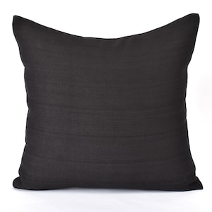 Könnte beinhalten: Ein schwarzes quadratisches Kissen mit einem dezenten strukturierten Stoff.