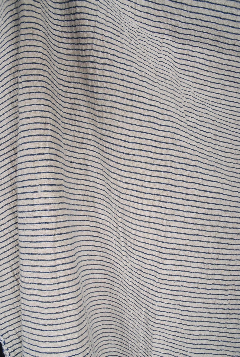 Peut inclure: Gros plan sur un tissu blanc &agrave; fines rayures bleu fonc&eacute;. Le tissu est froiss&eacute; et a une surface textur&eacute;e.