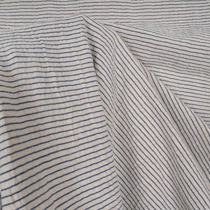 Peut inclure: Gros plan sur un tissu blanc &agrave; fines rayures bleues. Le tissu est pli&eacute; et froiss&eacute;, cr&eacute;ant un aspect textur&eacute;.