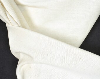 Könnte beinhalten: Nahaufnahme eines weißen Stoffes mit strukturierter Oberfläche. Der Stoff ist gefaltet und über eine schwarze Oberfläche gelegt.