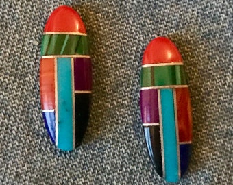 May include: A pair of oval-shaped earrings with a geometric design made of inlaid stones. The stones are red, orange, green, blue, purple, and black.