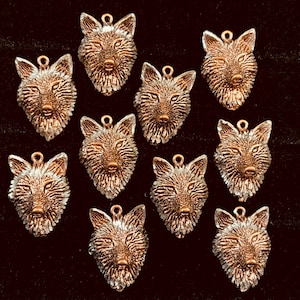 May include: Ten silver-colored wolf head charms with a textured finish. The charms have a loop at the top for attaching to jewelry or other crafts.