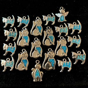 May include: A collection of 20 silver charm pendants featuring turquoise-inlaid cats in various poses. The charms are perfect for jewelry making or adding a touch of whimsy to any project.
