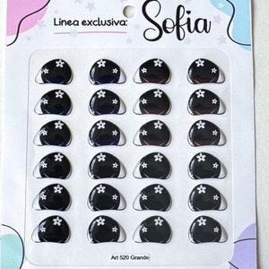 May include: A sheet of 18 black and white self-adhesive eyes with white flower designs. The eyes are arranged in six rows of three. The sheet is labeled "Linea exclusiva: Sofia" and "Art 520 Grande" and "Ojos3D Autoadhesivos Industria Argentina".