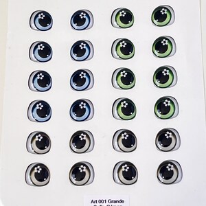 May include: A sheet of 24 doll eyes with a white flower design. The eyes are in four colors: blue, green, gray, and black. The sheet is labeled "Art 001 Grande Sofia G&oacute;mez".