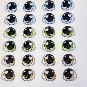 May include: A sheet of 24 plastic doll eyes with a heart design. The eyes are in various colors, including blue, green, and brown.
