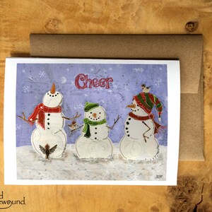 Carte de voeux de Noël représentant trois bonhommes de neige avec trois oiseaux et les mots « Cheer » - Vierge à l'intérieur