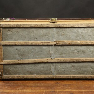 May include: A vintage wooden trunk with metal accents and a metal bottom. The trunk has a worn, distressed look and is secured with brass clasps.