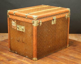 May include: A vintage brown leather travel trunk with brass hardware and a label that reads "Moynat Paris London".
