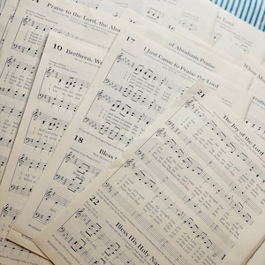 May include: A close-up of several pages of sheet music with musical notation and lyrics. The pages are stacked on top of each other and have a light brown color. The lyrics include "Praise to the Lord, the Almighty", "Brethren, We", "I Just Came to Praise the Lord", "The Joy of the Lord", "Bless the Lord", and "Bless His Holy Name".