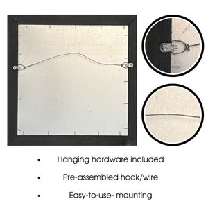 May include: Back of a framed artwork with a black frame, silver backing, and pre-installed hanging hardware. The image shows a wire and hooks for easy mounting. Text on the image states: "Hanging hardware included", "Pre-assembled hook/wire", and "Easy-to-use- mounting".