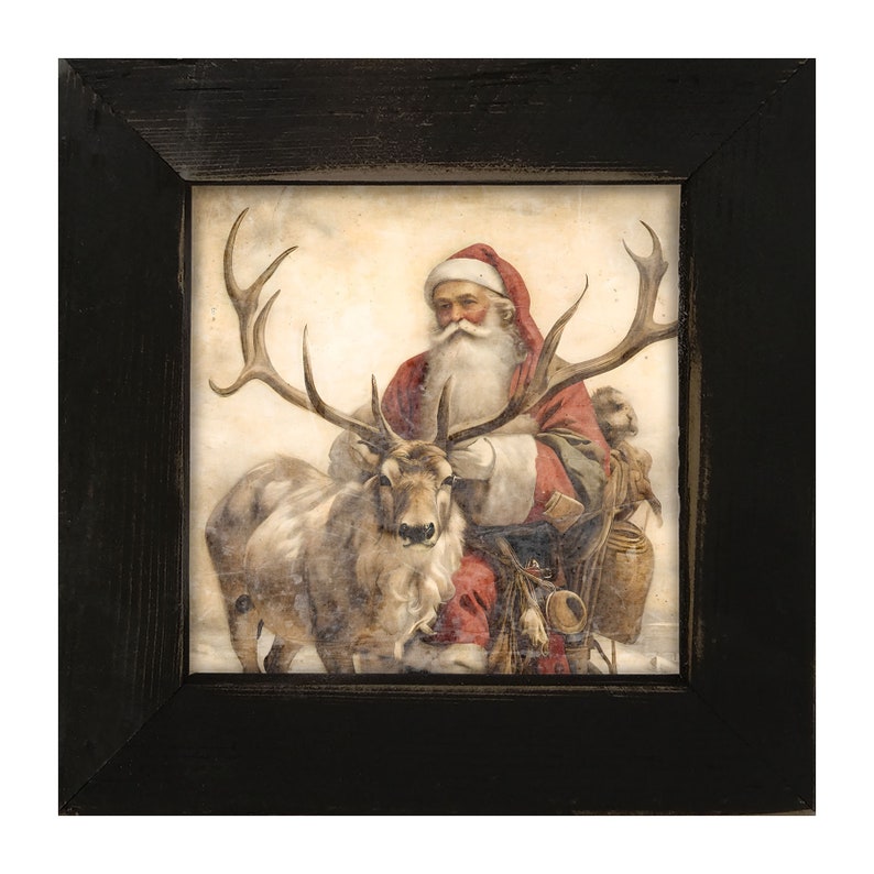 May include: A framed print featuring Santa Claus in a red suit and hat, with a long white beard, seated next to a reindeer. The artwork has a vintage style and is set against a light background. The frame is black.