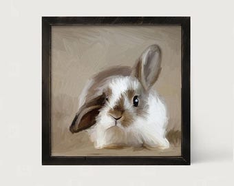 May include: A square framed wall art piece featuring an oil painting of a small rabbit with white and brown fur. The rabbit is depicted with one ear upright and one ear folded down, set against a neutral, textured beige background.