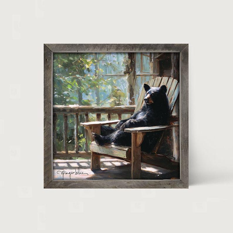 May include: A square framed painting depicting a black bear sitting in a wooden Adirondack chair on a porch. The scene features green foliage in the background and the signature Ginger Blue in the bottom left corner of the artwork.