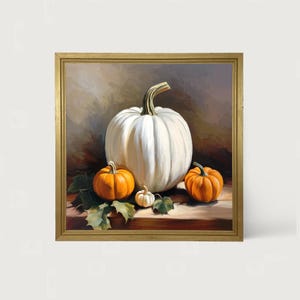 May include: A framed painting featuring a large white pumpkin with a curved stem, surrounded by three smaller orange pumpkins and green leaves. The artwork has a warm color palette and is set against a neutral background, evoking a harvest theme.