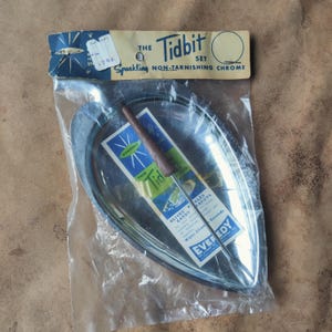 May include: A vintage "The Tidbit Set" in original packaging. The set includes a chrome serving dish and a serving utensil with a wooden handle. The packaging reads "Sparkling Non-Tarnishing Chrome".