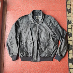 May include: Black leather jacket with a collared neckline, two front pockets, and a zipper closure. The jacket has a ribbed hem and cuffs. The text "ECHTES LEDER" is visible on the label. A classic outerwear piece.