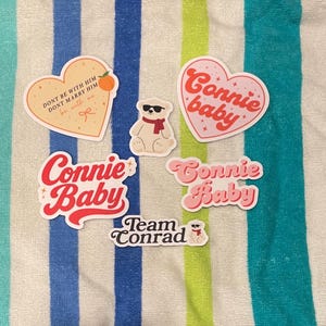 May include: A collection of stickers with various designs and text. Several stickers feature the words "Connie Baby" in different fonts and colors. Other stickers include a heart with text, a bear wearing sunglasses, and the words "Team Conrad".