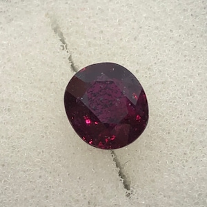 May include: A deep purple gemstone with a faceted cut.