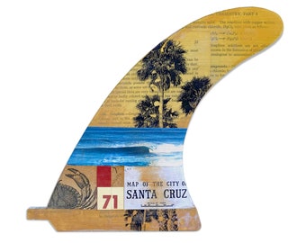 May include: A surfboard fin with a collage of images, including a map of Santa Cruz, California, palm trees, and a wave. The fin is made of wood and has a yellow, brown, and blue color scheme.